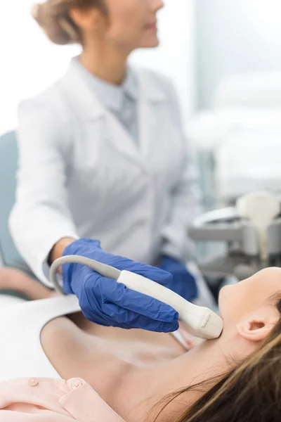 Selective focus of doctor examining thyroid of female patient with ultrasound scan in clinic — Stock Photo
