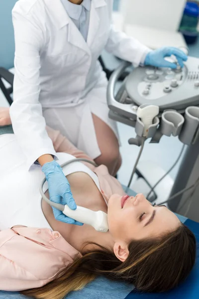 Doctor examining thyroid of female patient with ultrasound scan in clinic — Stock Photo