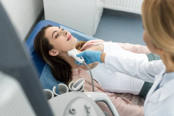 Doctor examining thyroid of beautiful patient with ultrasound scan in clinic — Stock Photo