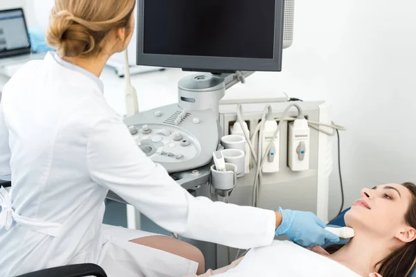 Professional doctor examining thyroid of patient with ultrasound scan and looking at blank screen — Stock Photo