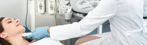 Panoramic shot of doctor examining thyroid of female patient with ultrasound scan in clinic — Stock Photo