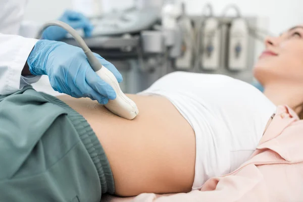 Vista recortada del médico examinando el estómago del paciente con ecografía - foto de stock