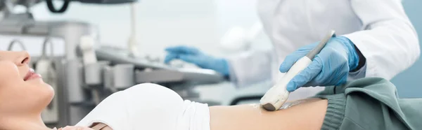 Tiro panorâmico do médico examinando o estômago do paciente sorridente com ultra-som na clínica — Fotografia de Stock