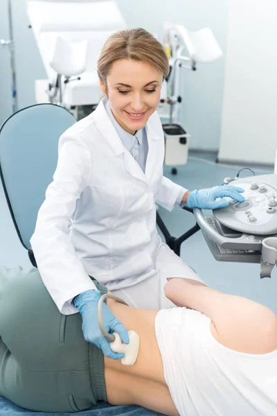 Profesional médico sonriente examinando riñón de paciente femenina con ecografía en clínica - foto de stock