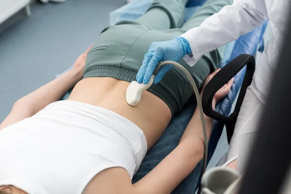 Teilansicht des professionellen Arztes bei der Untersuchung der Niere des Patienten mit Ultraschalluntersuchung in der Klinik — Stockfoto