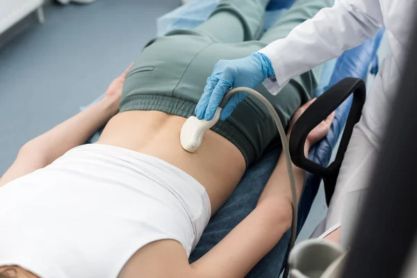 Vista parcial del médico profesional examinando el riñón del paciente con ecografía en la clínica - foto de stock