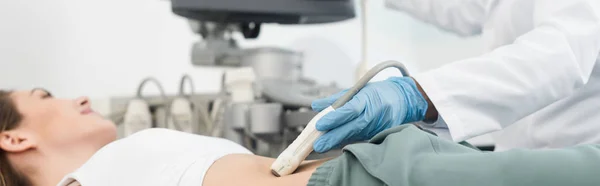 Panoramic shot of doctor making ultrasound scan of stomach in clinic — Stock Photo