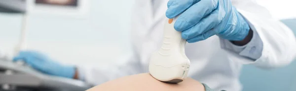 Панорамный снимок врача, осматривающего живот беременной женщины с помощью ультразвукового сканирования в клинике — стоковое фото