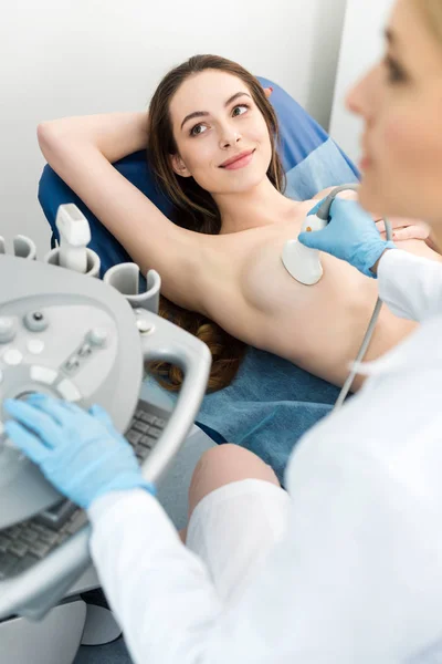 Médecin faisant un examen mammaire pour le patient souriant à l'aide d'un scanner à ultrasons — Photo de stock