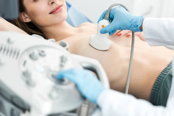 Cropped view of doctor making breast examination for patient using ultrasound scanner — Stock Photo