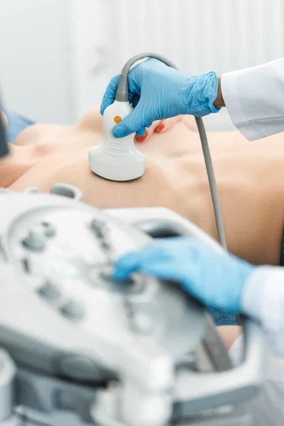 Vista parcial del médico que realiza el examen de mama para la paciente utilizando el escáner de ultrasonido en la clínica - foto de stock