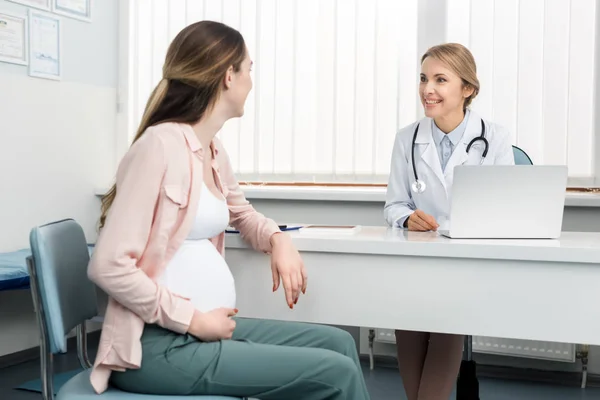 Mujer embarazada joven teniendo consulta con el médico en la clínica ginecológica - foto de stock