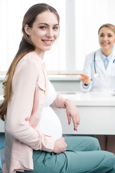 Heureuse femme enceinte ayant une consultation avec gynécologue en clinique — Photo de stock
