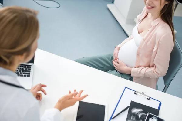 Jeune femme enceinte heureuse en consultation avec un médecin dans une clinique gynécologique — Photo de stock