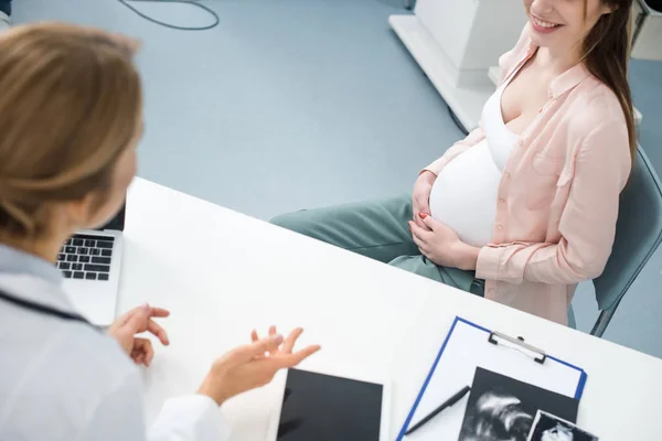 Jeune femme enceinte heureuse en consultation avec un médecin dans une clinique gynécologique — Photo de stock