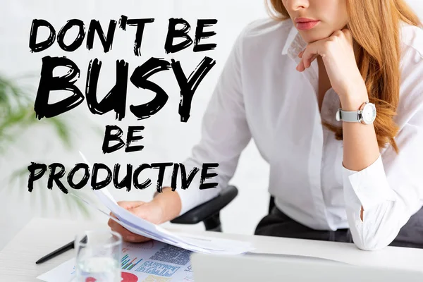 Cropped view of businesswoman holding dossier near graphs and laptop on table, don't be busy be productive illustration — Photo de stock