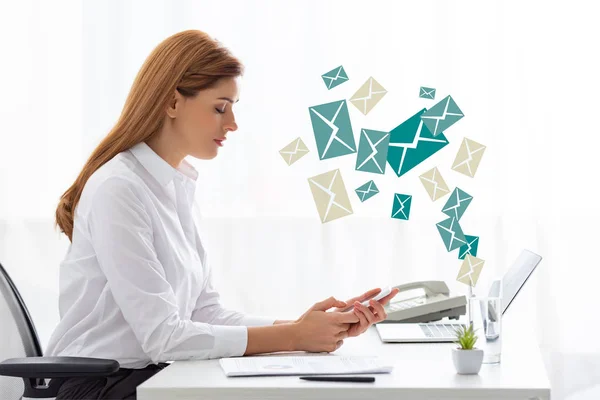 Vista lateral de la mujer de negocios utilizando el teléfono inteligente cerca de los documentos y el ordenador portátil en la mesa, ilustración de correo electrónico — Stock Photo