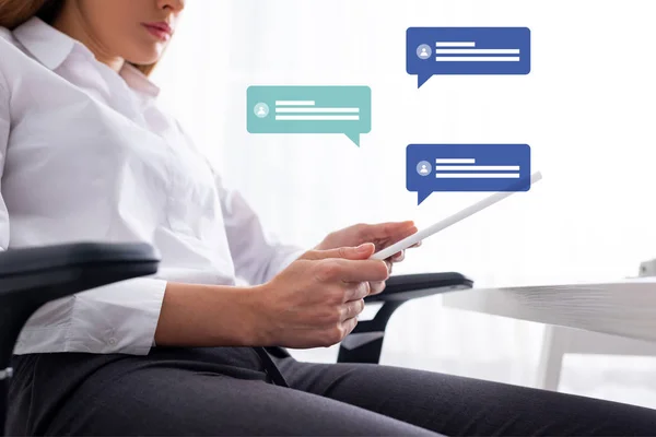 Low angle view of businesswoman using digital tablet while sitting at table, speech bubbles illustration — Stock Photo