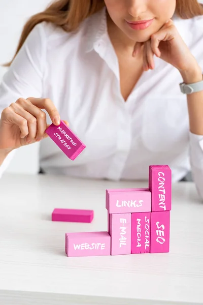 Enfoque selectivo de la mujer de negocios apilando pirámide de marketing con bloques de construcción de color rosa aislados en gris, ilustración de estrategia de marketing - foto de stock