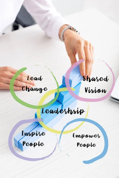 Cropped view of businesswoman stacking blue building blocks near laptop on table, leadership illustration — Stock Photo