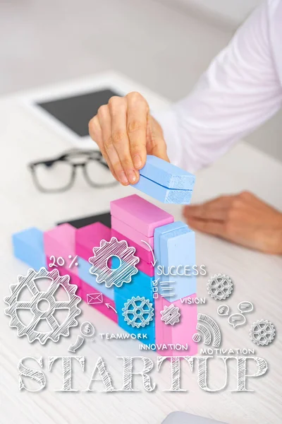 Обрезанный вид предпринимательницы, делающей маркетинговую пирамиду из красочных строительных блоков на столе, иллюстрация стартапа — стоковое фото
