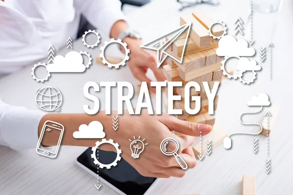 Cropped view of businesswoman playing blocks wood tower game near smartphone at table, strategy illustration — Stock Photo