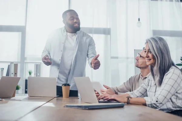 Empresario afroamericano hablando con colegas durante reunión en agencia creativa - foto de stock