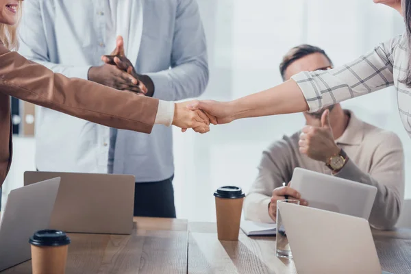 Cropped view of colleagues shaking hands during meeting in creative agency — Stock Photo