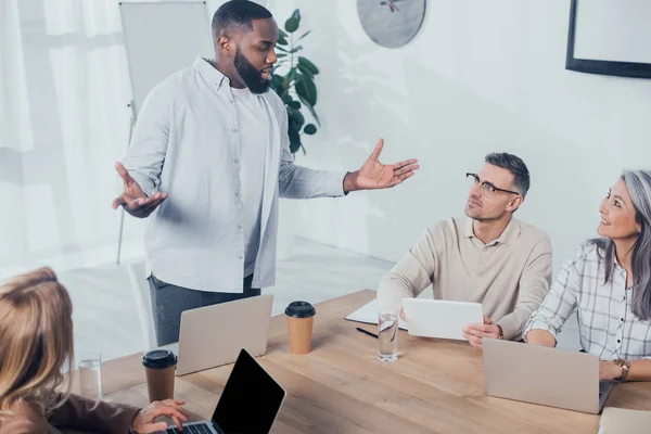 Афроамериканський чоловік розмовляє з колегами під час зустрічі у творчому агентстві — стокове фото