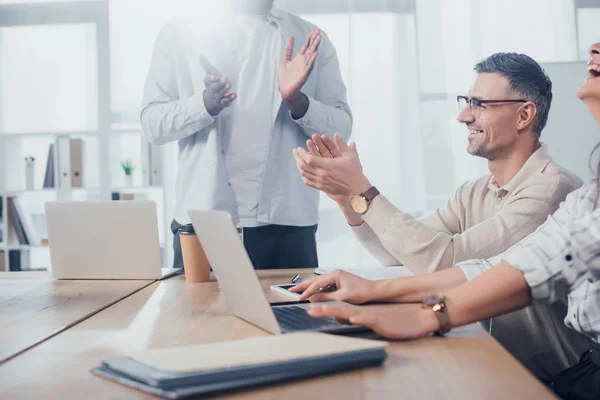 Cropped view of smiling multicultural colleagues clapping during meeting in creative agency — Stock Photo