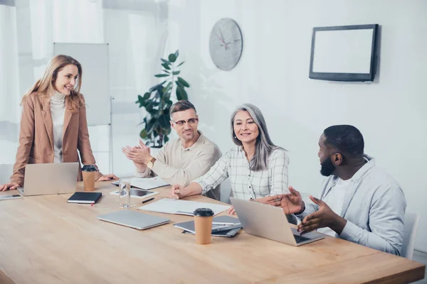 Smiling multicultural colleagues talking during meeting in creative agency — Stock Photo