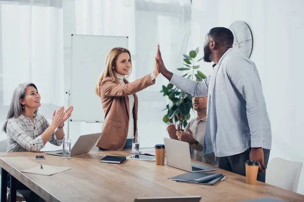 Sorridenti colleghi multiculturali applaudono e danno il cinque in agenzia creativa — Foto stock