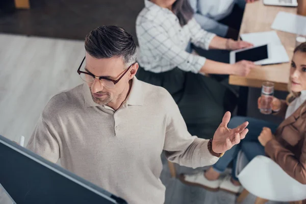 Selective focus of businessman writing on flipchart during presentation for multicultural colleagues — Stock Photo