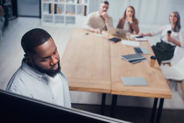 Hochwinkelaufnahme eines afrikanisch-amerikanischen Geschäftsmannes, der während der Präsentation auf das Flipchart blickt — Stockfoto