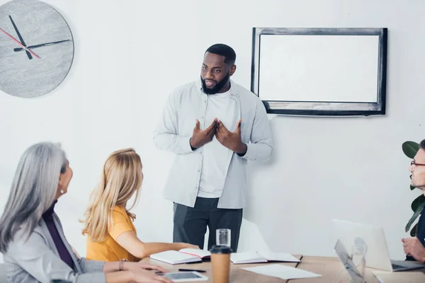 Sorridente empresário afro-americano conversando com seu colega na agência criativa — Fotografia de Stock