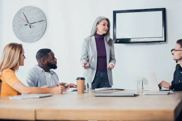 Asiático mujer de negocios hablando con multicultural colegas en oficina - foto de stock