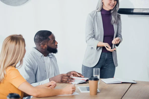 Vue recadrée d'une femme d'affaires souriante parlant avec des collègues multiculturels — Photo de stock