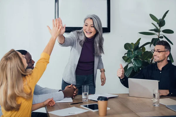 Smiling multicultural colleagues giving high five and showing like — Stock Photo