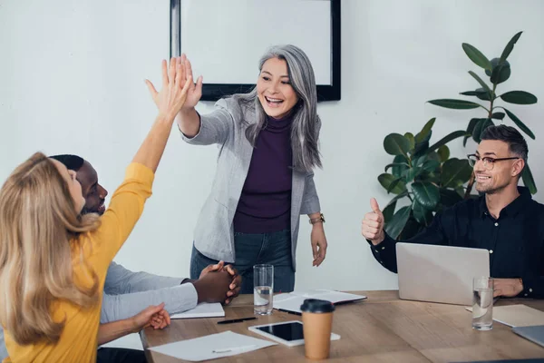 Sonrientes colegas multiculturales dando choca esos cinco y mostrando como — Stock Photo