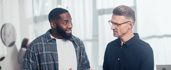 Panoramic shot of smiling african american businessman talking with his colleague — Stock Photo