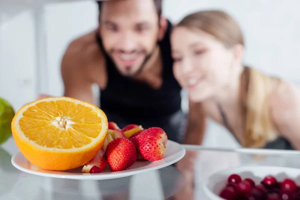 Messa a fuoco selettiva di frutti gustosi in frigorifero vicino a uomo e donna felice — Foto stock