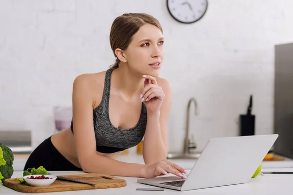 Pensive girl near credit card and laptop in kitchen — Stock Photo