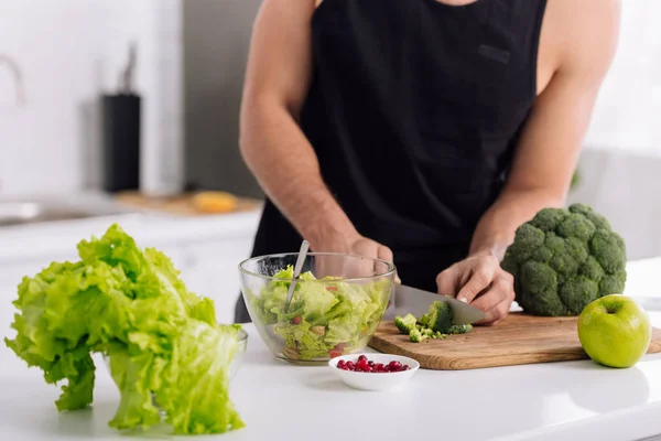 Abgeschnittene Ansicht eines Mannes, der Brokkoli auf Schneidebrett schneidet — Stockfoto