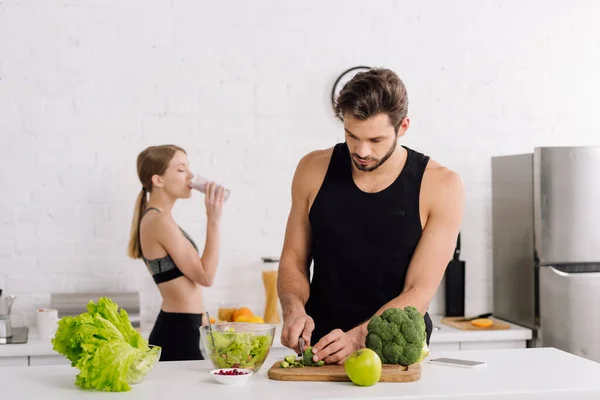 Selective focus of handsome man cooking near girl drinking smoothie — Stock Photo