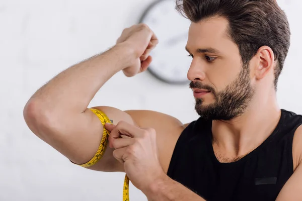 Handsome and sportive man measuring muscle on hand — Stock Photo