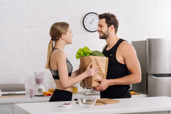 Seitenansicht von glücklichen Mädchen und bärtigen Mann mit Papiertüte mit Lebensmitteln — Stockfoto
