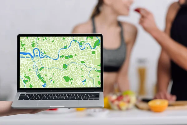 Selective focus of laptop with online map near couple in kitchen — Stock Photo