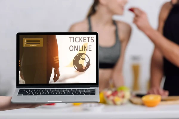 Selective focus of laptop with tickets online website on screen near couple in kitchen — Stock Photo