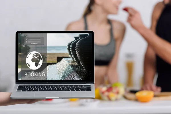 Selective focus of laptop with booking website on screen near couple — Stock Photo