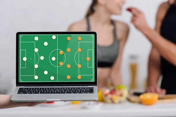 Selective focus of laptop with tactical scheme on screen near couple in kitchen — Stock Photo